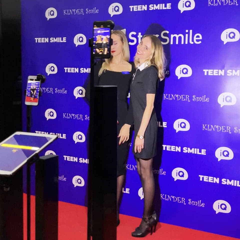 Two women are using Red Carpet Photobooth. Several cameras shoot them from different angles and instantly prepare the content.